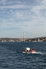 View of a traditional, small fishing boat on Bosphorus and bridge in Istanbul. It is a sunny summer day.