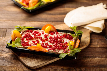 Mutabal with pomegranate seeds and salad served in a dish isolated on wooden table background side view of fastfood