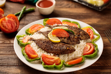 Safi fried fish with rice, tomato, lime and dip served in a dish isolated on wooden table background side view of fastfood