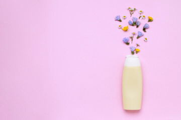 Yellow bottle with flowers on colorful pink background in minimal style top view flat lay with space for text copy space. bio organic eco natural product beauty and spa