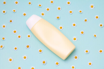 Yellow bottle with chamomile flowers on colorful blue background. bio organic eco natural product beauty and spa