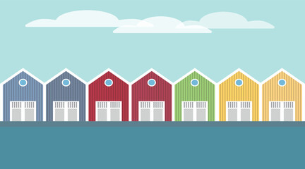 Bunte skandinavische Häuser mit einem See im Vordergrund und Wolken im Hintergrund.