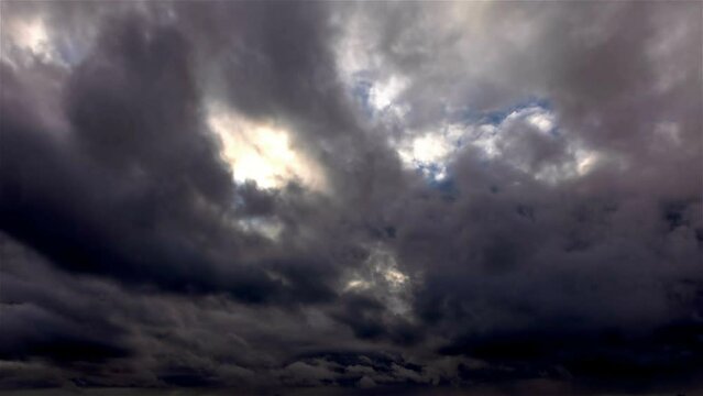 big dark rain clouds move across the sky blocking out the sun time lapse
