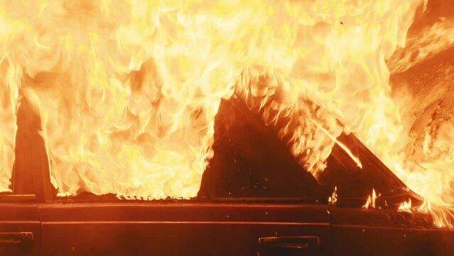 Close up fired around part of burning car on the street in the city. Automobile engulfed in flames of fire. Explosion. Bomb. Car crash. Burning wheel. Emergency