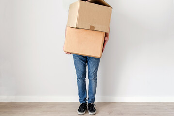 Un hombre joven sujetando dos cajas de cartón. Sin mostrar el rostro. Concepto de mudanza y...