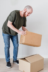 Un hombre joven con barba agarra una caja de cartón. Concepto de mudanza y amueblar un nuevo hogar.