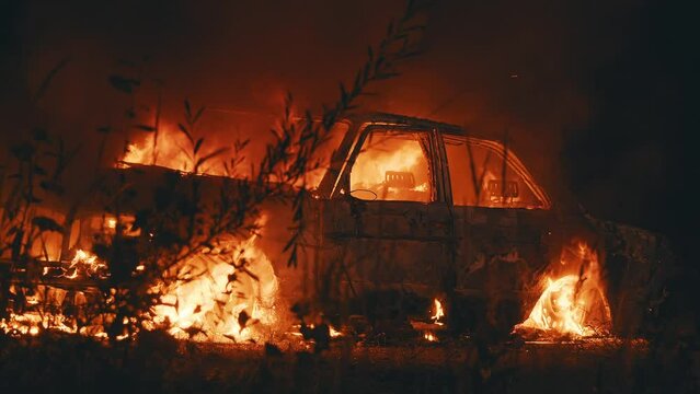 At night burning car on the street in the cit orange fired around. Automobile engulfed in flames of fire. Explosion. Bomb. Car crash. Burning wheel. Emergency