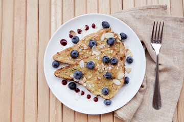 Traditional whole grain sandwiches with fresh blueberries, almond flakes and agave syrup on a plate. Sweet breakfast on the terrace