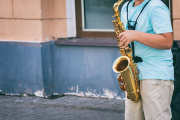 young man is street musician playing saxophone on the street, Jazz festival, musical background, toned