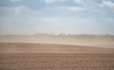 Fotobehang Sandstorm over farmland. Silence and wind blowing a cloud of dust. The impact of drought on crops and agriculture in Europe. © PhotoRK