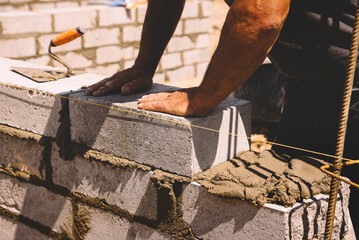 Professional construction worker laying bricks and mortar - building external house walls....