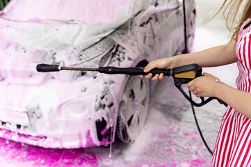 car in pink foam standing at a self-service car wash. car cleaning. removing dirt from the car....