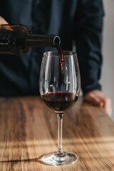 Close-up of a man sommelier pouring red wine from a bottle into a glass