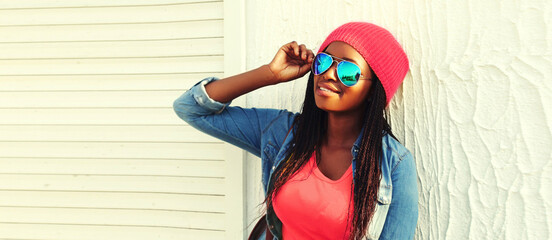 Portrait of happy smiling young african woman model wearing sunglasses, pink hat, colorful clothes...