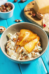 Pear and gorgonzola oatmeal with walnuts on blue wooden table