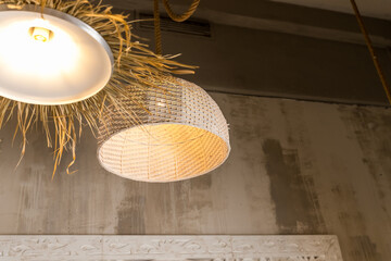 Low angle view of two handmade and wicker lampshade with natural materials hanging in living room....