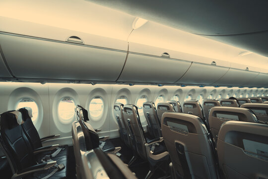 A Wide-angle View Of A Long Cabin Of A Passenger Plane With Empty Rows Of Plastic Seats In Economy Class Of The Airplane With Safety Instructions In The Pockets On The Other Sides Of Them