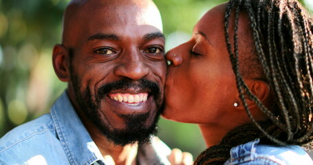 Fototapeta premium African girl kissing man in cheek outside, happy black people