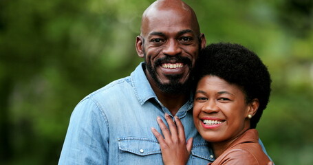 African couple embracing together outside portraits looking at camera standing outside
