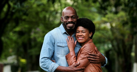 African couple embracing together outside portraits looking at camera standing outside