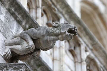 Monstrous statue with almost human features called gargoyle on the historic building