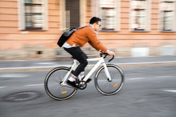 A blurry photo in motion. A male cyclist rides a bicycle to work in the city, ecotransport.