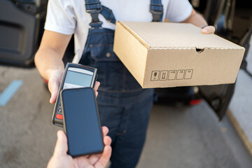 NFC payment for delivery male courier service employee, driver delivery of goods in boxes.