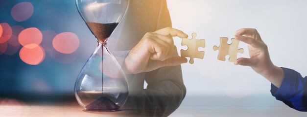 Hands putting puzzle pieces with clock