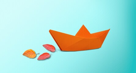 Paper boat with fresh tree leaves on blue background.