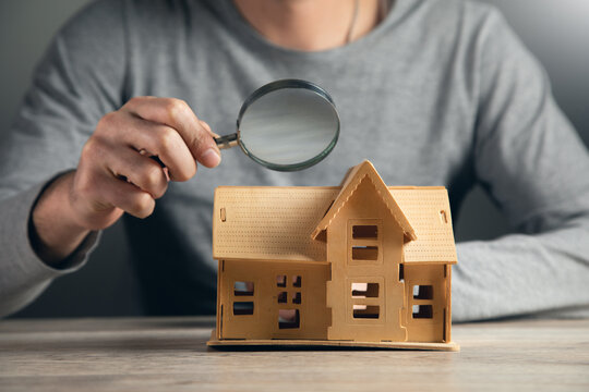 Hand Of Businessman Hold Magnifying Glass Looking House