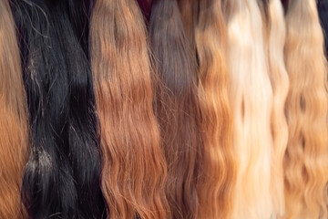 Multicolor locks of hair for hair extensions - blond, brown, red, black: close up. Strand of natural hair in row. Glamour, beauty and haircare concept