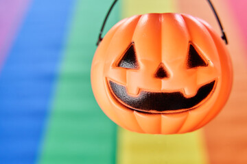Smiling Halloween pumpkin head basket hanging with lgbt pride flag on background