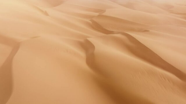 Drone footage of large steep dune riding area below hot summer sun. Huge desert floor with hilly landscape as seen from above. High quality 4k footage