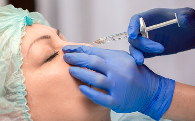 Cosmetic procedure for non-surgical rhinoplasty. Beautician injects hyaluronic acid into the nose...