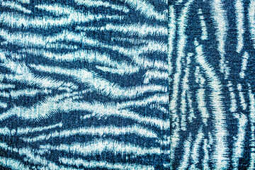 Jeans background. Denim fabric closeup. Textures of clothing fabric with fashion embroidery blue...