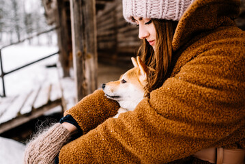 Cute young girl having fun in the winter park with their dog on bright day.Woman are relaxing