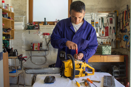 Image of a mechanic in his workshop repairing a chainsaw. Manual and do-it-yourself jobs.
