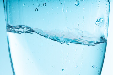 Naklejka na ściany i meble blue splash of water in a glass vessel