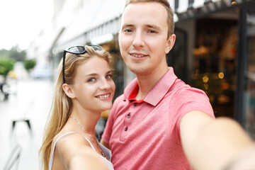 Smiling beautiful girl and her boyfriend in casual summer clothes. Happy family taking selfie self...