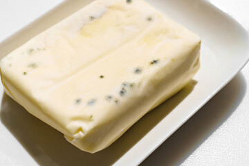 a pack of spoiled butter with mold on a white background. 