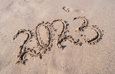 New year 2023. Figures on the sandy seashore.