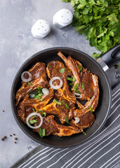 Raw marinated lamb meat on a frying pan. Lamb meat ready to cook. Top view