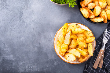 Baked potato segments with spices on a plate. Top view, copy space