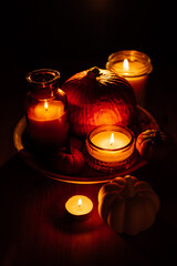 Autumn thanksgiving home decor with pumpkins and burning candles on table. Dark moody banner decorations with pumpkin and candles