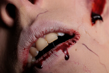 Apocalyptic zombie with bloody lips and teeth, showing wounded mouth with blood on camera. Scary...