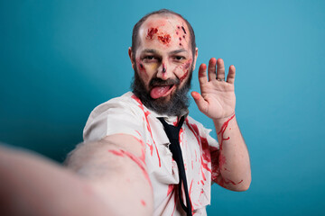 Creepy eerie zombie taking picture on camera, posing in studio and looking dangerous. Brain eating...