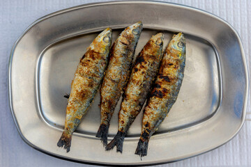 Traditional Portuguese dish with unique flavour to cook with high quality grill in summer, Grilled marinated fresh sardines fish with sea salt in stainless plate or tray, Delicious Portugal food.