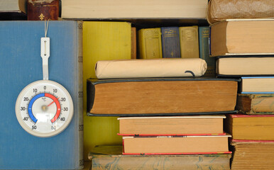 books and thermometer showing low temperature in a library due to shortage of heating gas and oil