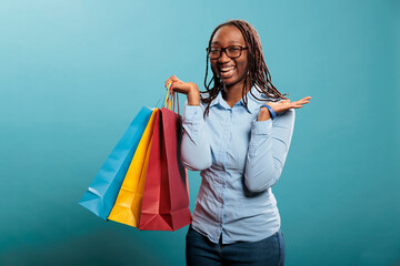 Excited and cheerful woman smiling with mouth wide open after buying stylish and fashionable store goods at mall. Beautiful and happy young lady joyful after purchasing clothing articles at discount.