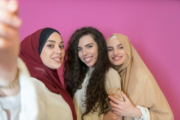 group of beautiful muslim women two of them in fashionable dress with hijab using mobile phone...
